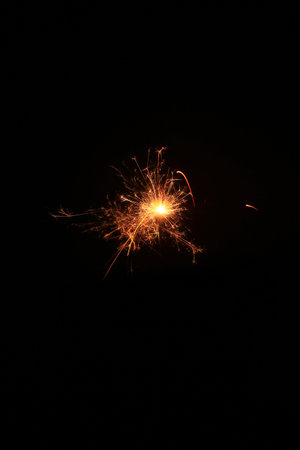Yellow sparks fly on a black background, layered with grain, noise, and glowing effects to give a...