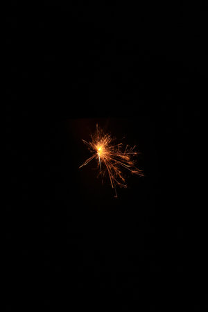 Yellow sparks fly on a black background, layered with grain, noise, and glowing effects to give a...