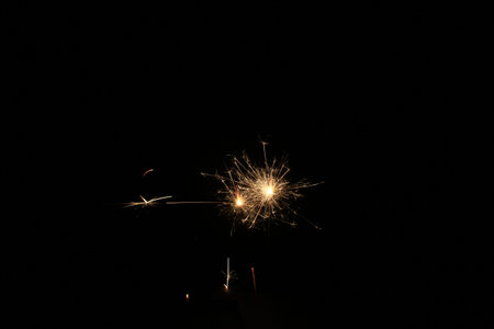 Yellow sparks fly on a black background, layered with grain, noise, and glowing effects to give a...