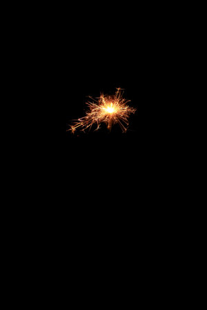 Yellow sparks fly on a black background, layered with grain, noise, and glowing effects to give a...