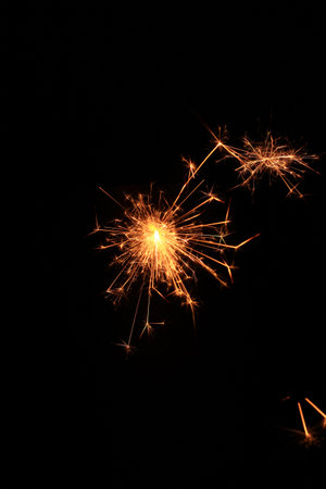 Yellow sparks fly on a black background, layered with grain, noise, and glowing effects to give a...