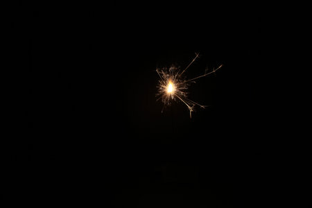 Burning sparkler on a black background. New Year's Eve.