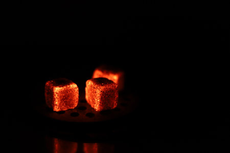 Glowing coals with glitch style lighting, enriched by noise, effect and grain details, create a mystical atmosphere in the dark. A vivid sense of heat and depth surrounds the imageの写真素材