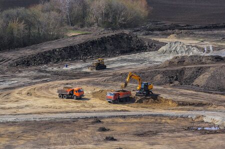 bulldozer, excavator and dump trucks on a construction siteの写真素材