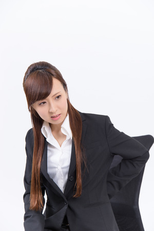 Young Japanese business woman has a bad lower back on white backgroundの写真素材