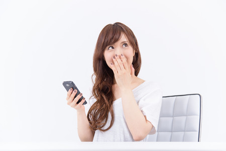 Young Asian woman with smartphone happy to see the good news.の写真素材