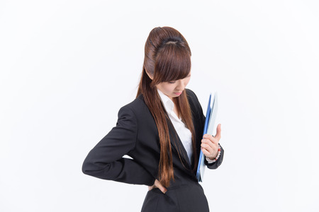 Young Japanese business woman has a bad lower back on white backgroundの写真素材
