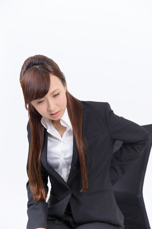 Young Japanese business woman has a bad lower back on white backgroundの写真素材