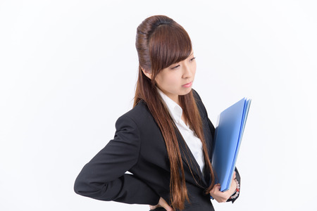Young Japanese business woman has a bad lower back on white backgroundの写真素材