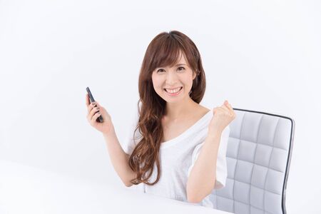 Young Asian woman with smartphone happy to see the good news.の写真素材