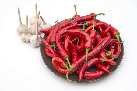 many red chili peppers and garlic on brown plate isolatedの写真素材