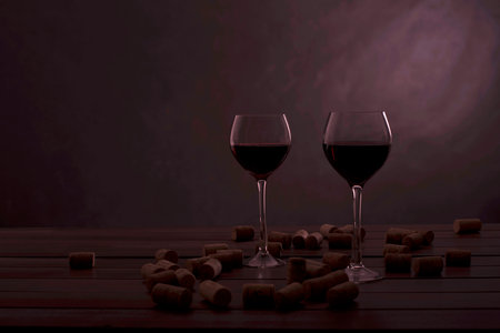 two glasses of wine on a table with jams on a black の写真素材