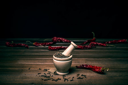 marble mortar with spices black pepper, carnation and red hot pepper on a wooden tableの写真素材