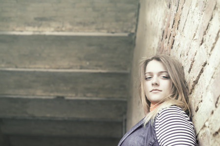 beautiful girl out of door against a wallの写真素材