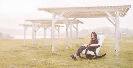 beautiful happy woman has a rest in chair on bank of the lake morningの写真素材