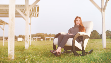 beautiful happy woman has a rest in chair on bank of the lake morningの写真素材