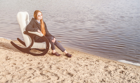 beautiful happy woman has a rest in chair on bank of the lake morningの写真素材