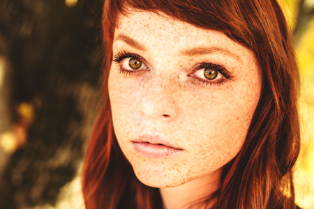 beautiful woman with red long hair in fall parkの写真素材