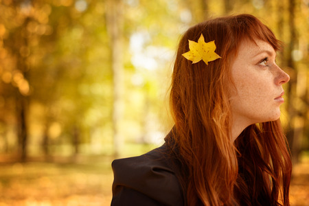 beautiful woman with red long hair in fall parkの写真素材