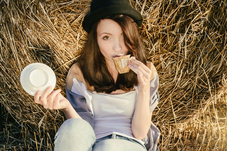 beautiful girl hipster drink tea against a hay bale in fallの写真素材