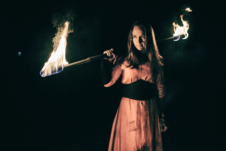 active the European girl in original suit carries out tricks for fire show at nightの写真素材