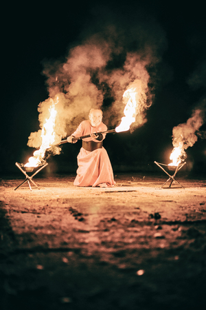 active the European girl in original suit carries out tricks for fire show at nightの写真素材