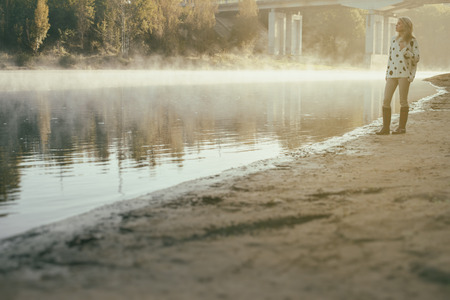 lonely beautiful girl walks on river bank early in the morningの写真素材