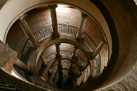 Spiral rounded ramp stairs. Into the dark, into the light. Rising up, going down Mystic lighting. Ancient historic walls and columns.のeditorial素材