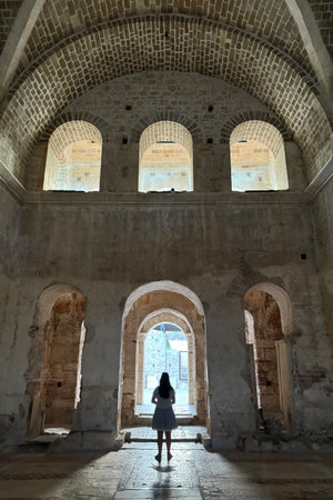 Interior view of ancient ruins showing stone arches and vaulted ceilings, with a silhouetted figure standing in an arched doorway, UNESCO World Heritage Site featuring architectural elements like keystones and columnsの写真素材