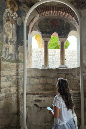 Back of tourist woman in ruins ancient medieval city old church Lycian rock tombs stone temple in Turkey, UNESCO World Heritage Site, top arches, keystones, columns, torsoの写真素材
