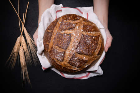 Artisan bread loaf with nice patterns held in female handsの写真素材