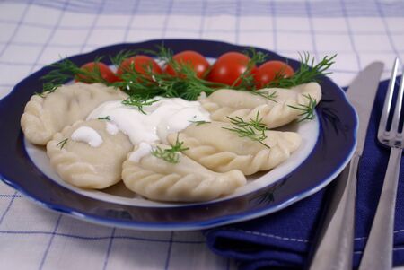 Dumplings with sour cream, decorated with tomatoesの写真素材