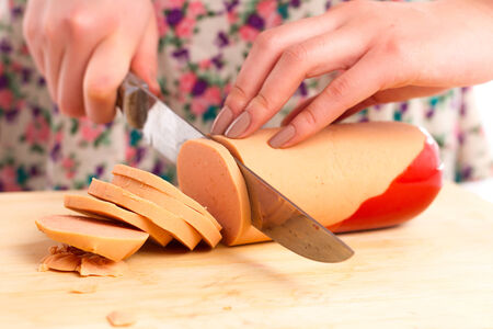 A housewife cutting sausage in the kitchenの写真素材