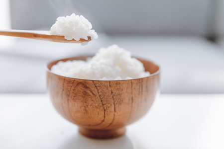 The wooden bowl is filled with rice.の写真素材