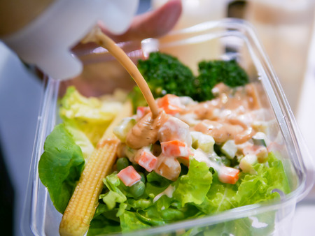 Salad with salad sauce flowing from bottle. Smooth light and shadow, high contrast.の写真素材