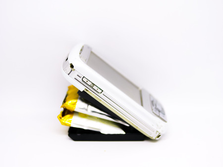Isolated swollen battery with a phone on white background.の写真素材