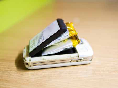 Isolated swollen battery with a phone on white background.の写真素材