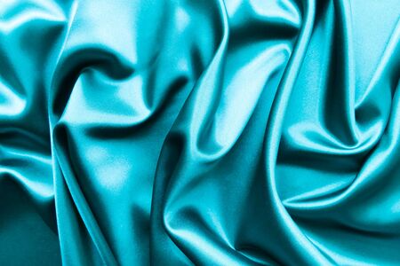 Smooth elegant wavy turquoise silk or satin luxury cloth fabric texture, abstract background design.の写真素材