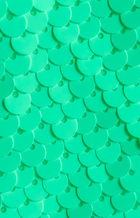 Background sequin. Holiday abstract glitter background with blinking lights. Fabric sequins in green color. Fashion fabric glitter, sequins. Wallpaper.の写真素材