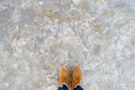 Top view of yellow shoes / boots standing on the ice near the sea. Winter season.