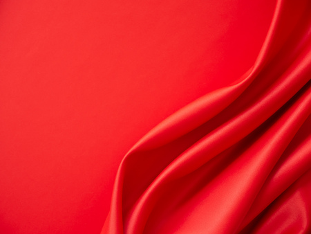 Beautiful smooth elegant wavy hot red satin silk luxury cloth fabric texture, abstract background design. Wallpaper, banner or card with copy space.の写真素材