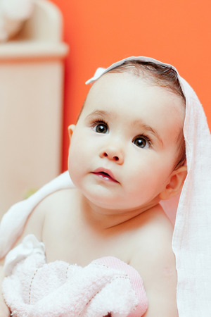 Cute baby, looking out under a white blanket / towel.の写真素材