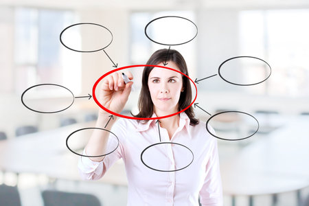 Young business woman writing diagram of centralization. Office background.
