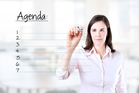 Young business woman writing blank agenda list. Office background.の写真素材