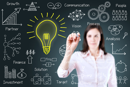 Young business woman writing business idea concept. Blue background.の写真素材