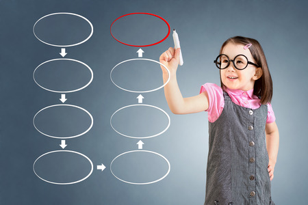 Cute little girl wearing business dress and drawing eight blank stage strategy flowchart. Blue background.の写真素材