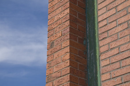 Formations and texture on a brick wall and a blue sky and clouds in a urban scene