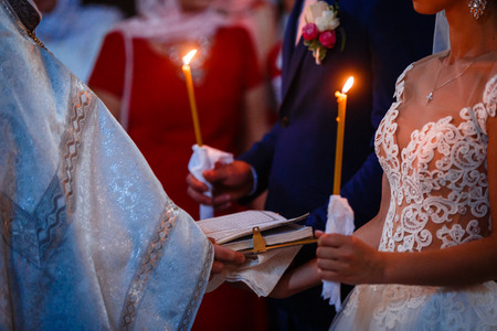 Bride and groom are holding each other's hands during church wedding ceremonyの写真素材