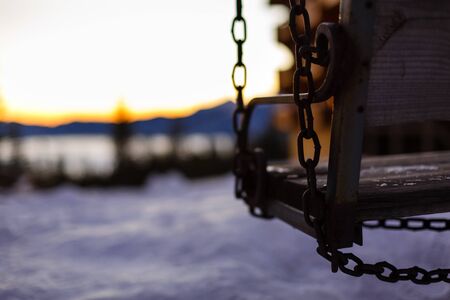 Abstract winter scene with a garden swing covered with snow, appearing to invite everyone to take a break, have a snack and enjoy the landscape and generally the unique moments of the life.の写真素材