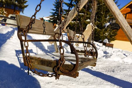 Abstract winter scene with a garden swing covered with snow, appearing to invite everyone to take a break, have a snack and enjoy the landscape and generally the unique moments of the life.の写真素材